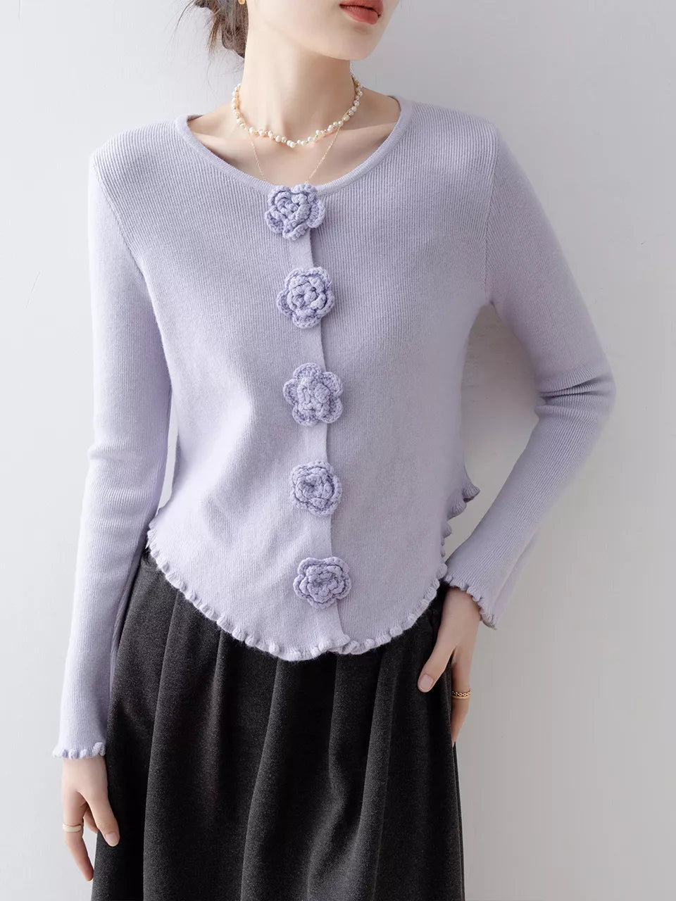 Elegantes, lila Stricktop mit Rundhalsausschnitt, floralen Details und Rüschen.